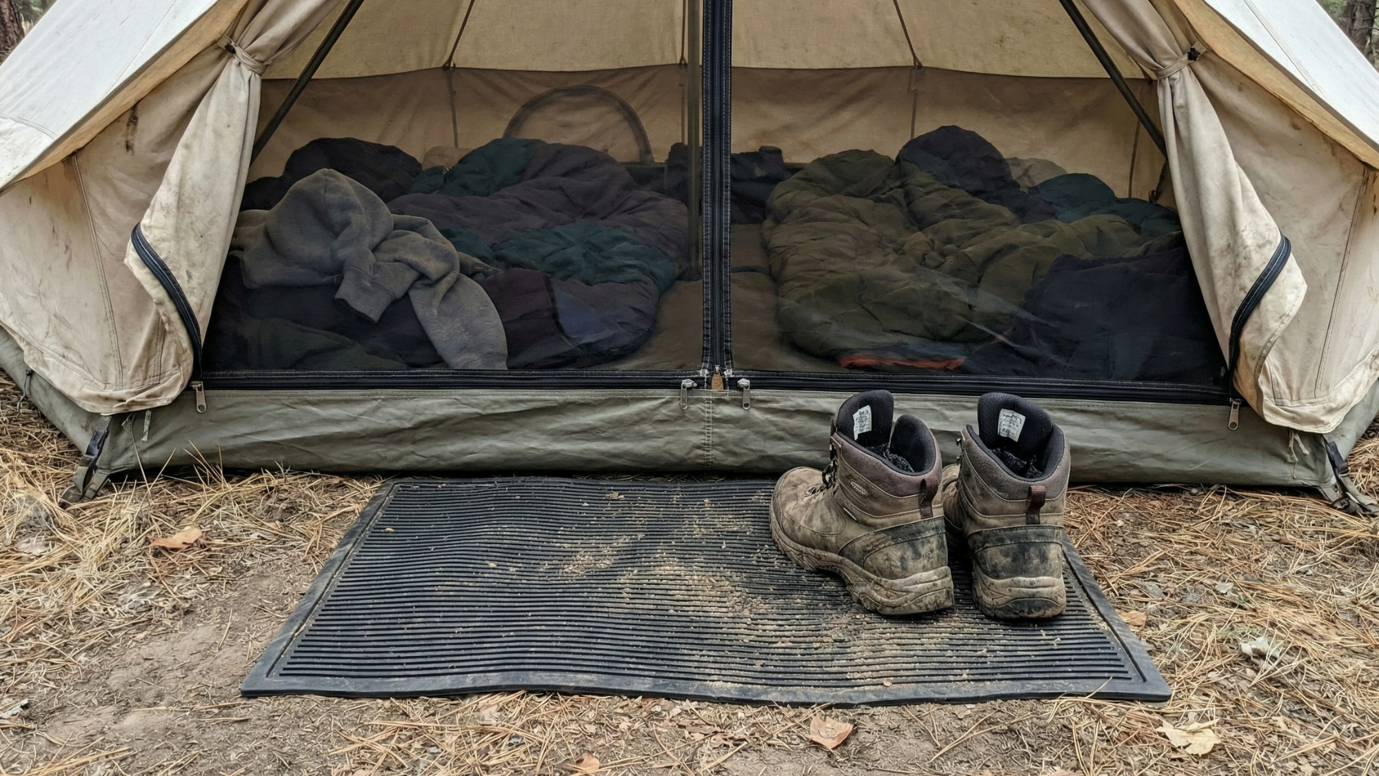 Hiking boots neatly placed on a rubber doormat outside a tent entrance at a campsite Hiking boots neatly placed on a rubber doormat outside a tent entrance at a campsite