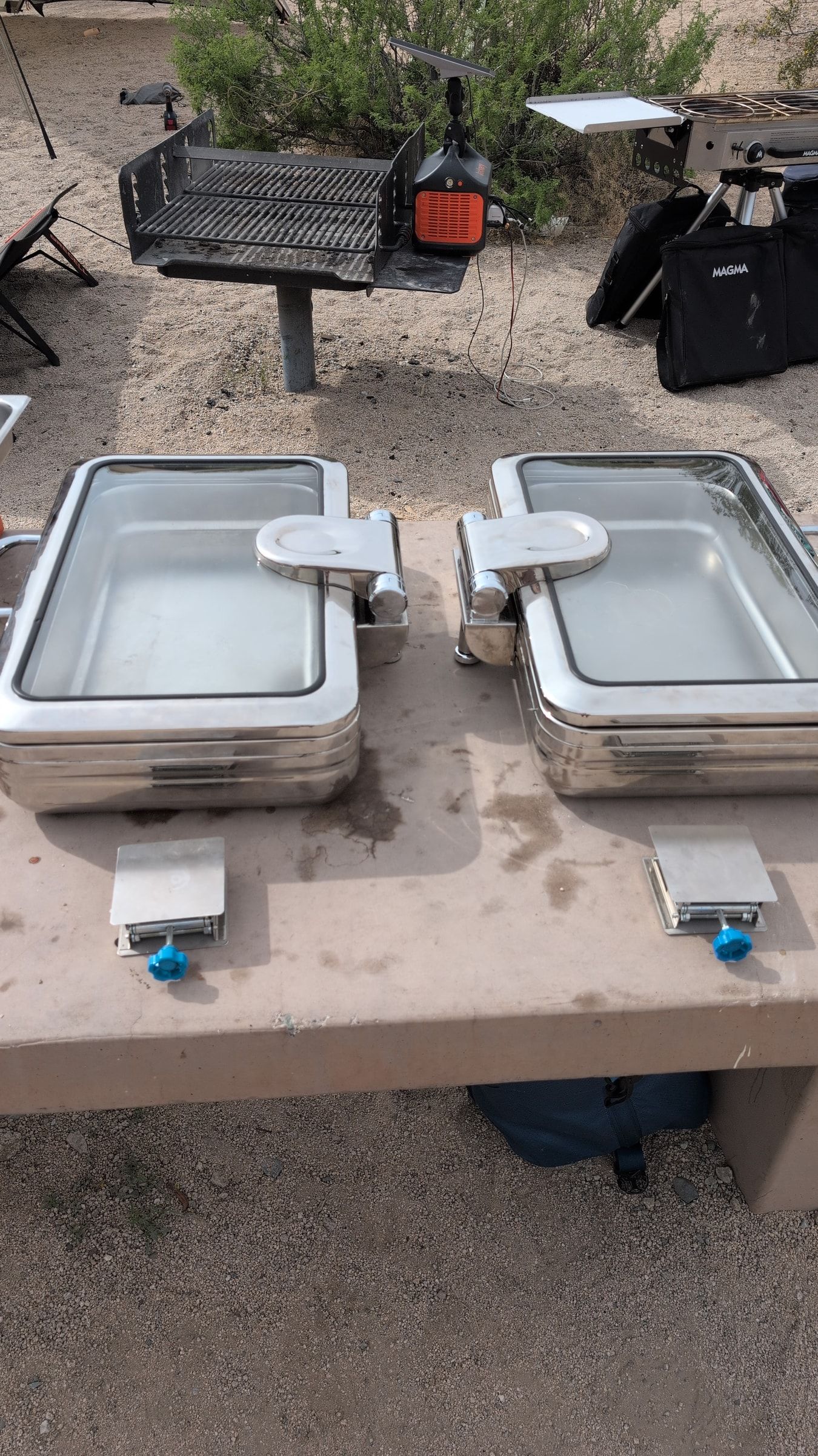 Photo of two chafing dishes and metal risers laid out on the camp table