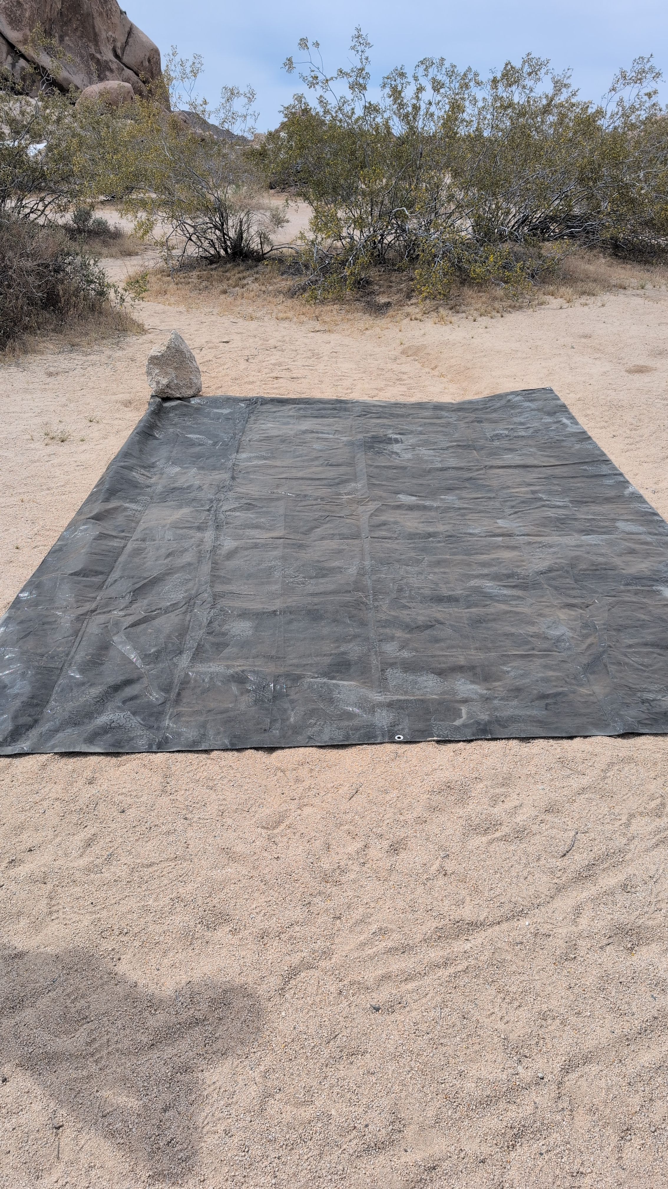 Photo of ground sheet laid flat on cleared campsite with space for vestibule on one side
