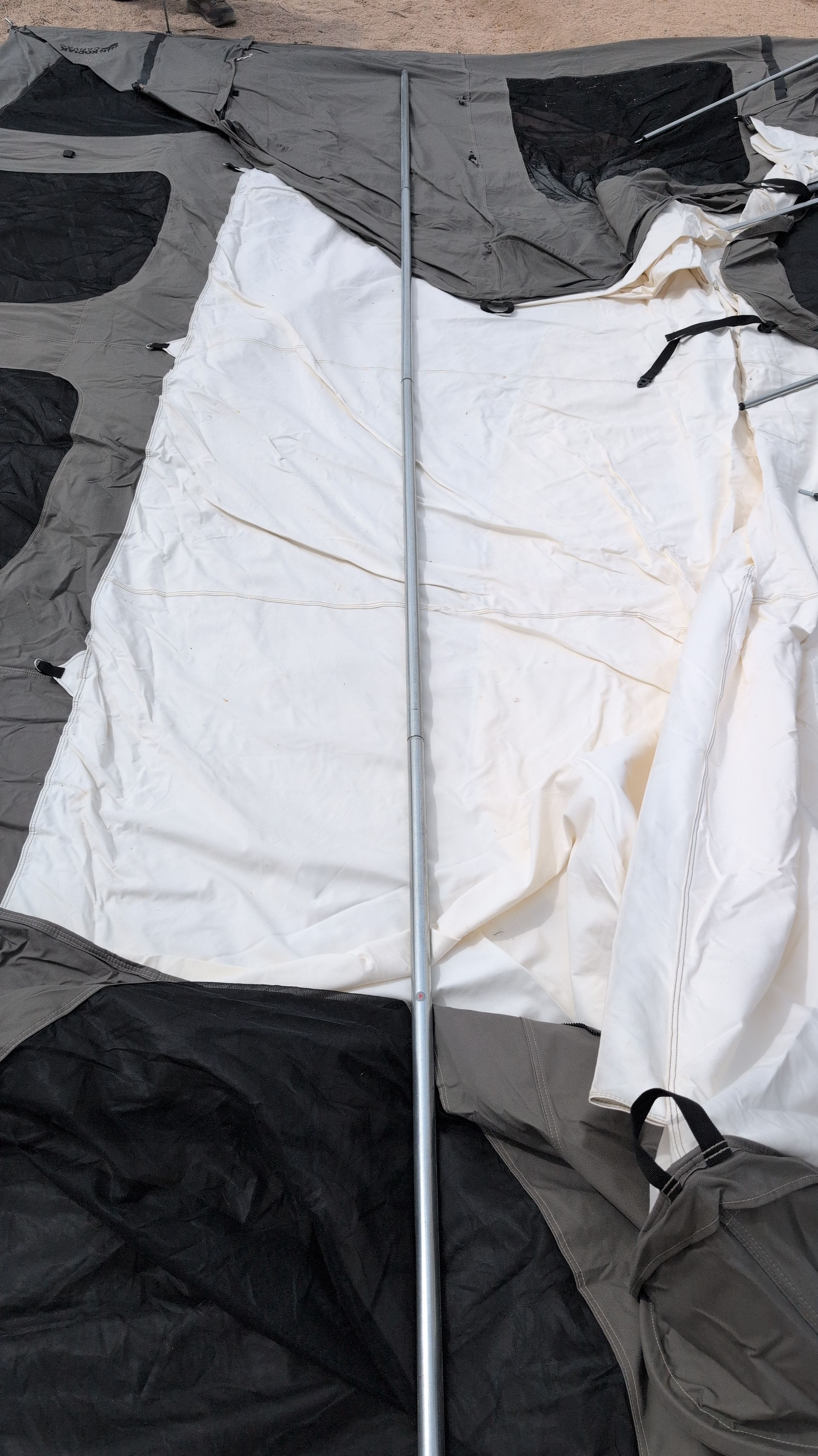Photo of the long center ridge pole laid out next to the tent before threading