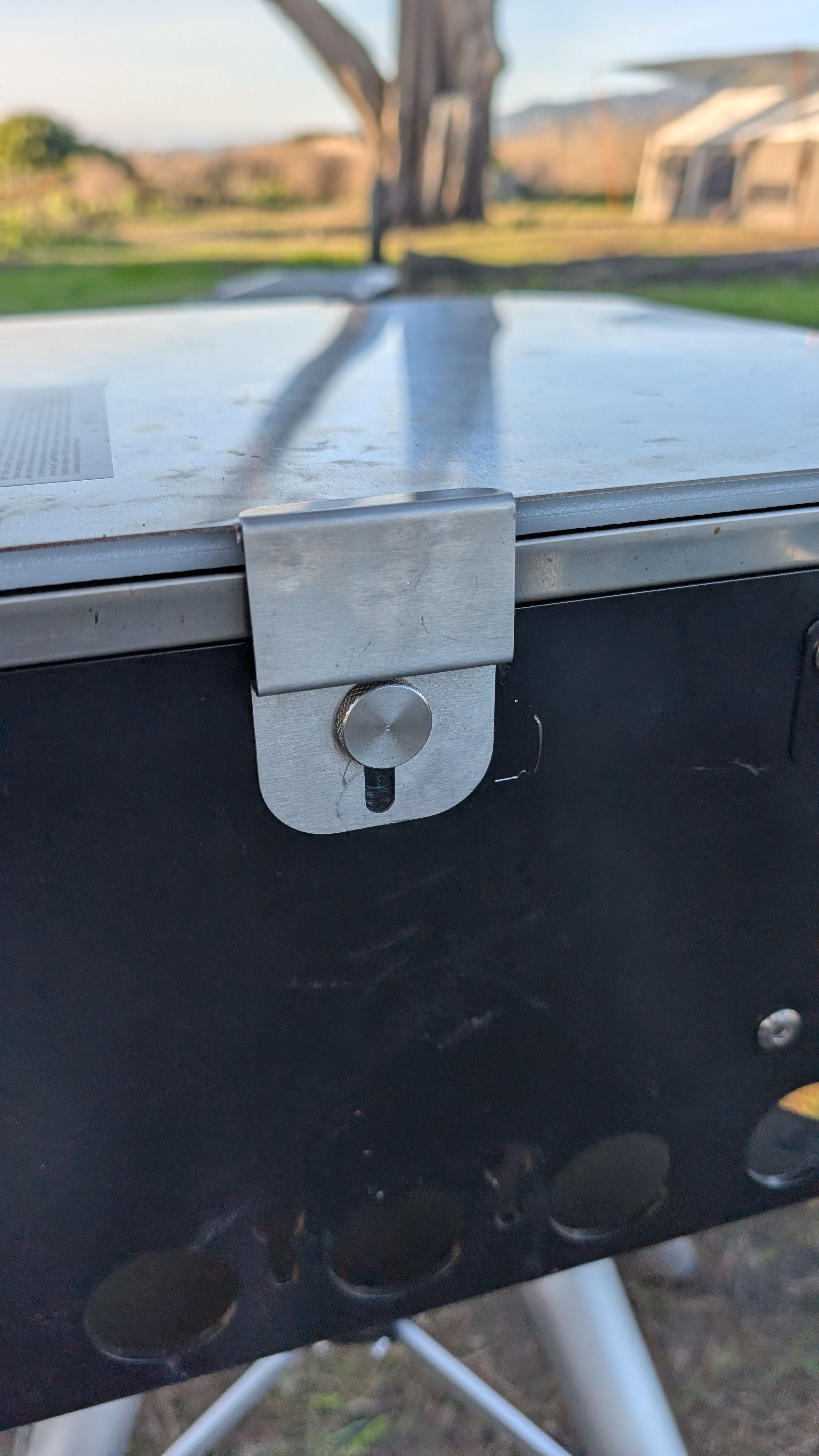 Close-up of lid latch clip holding the grill cover closed
