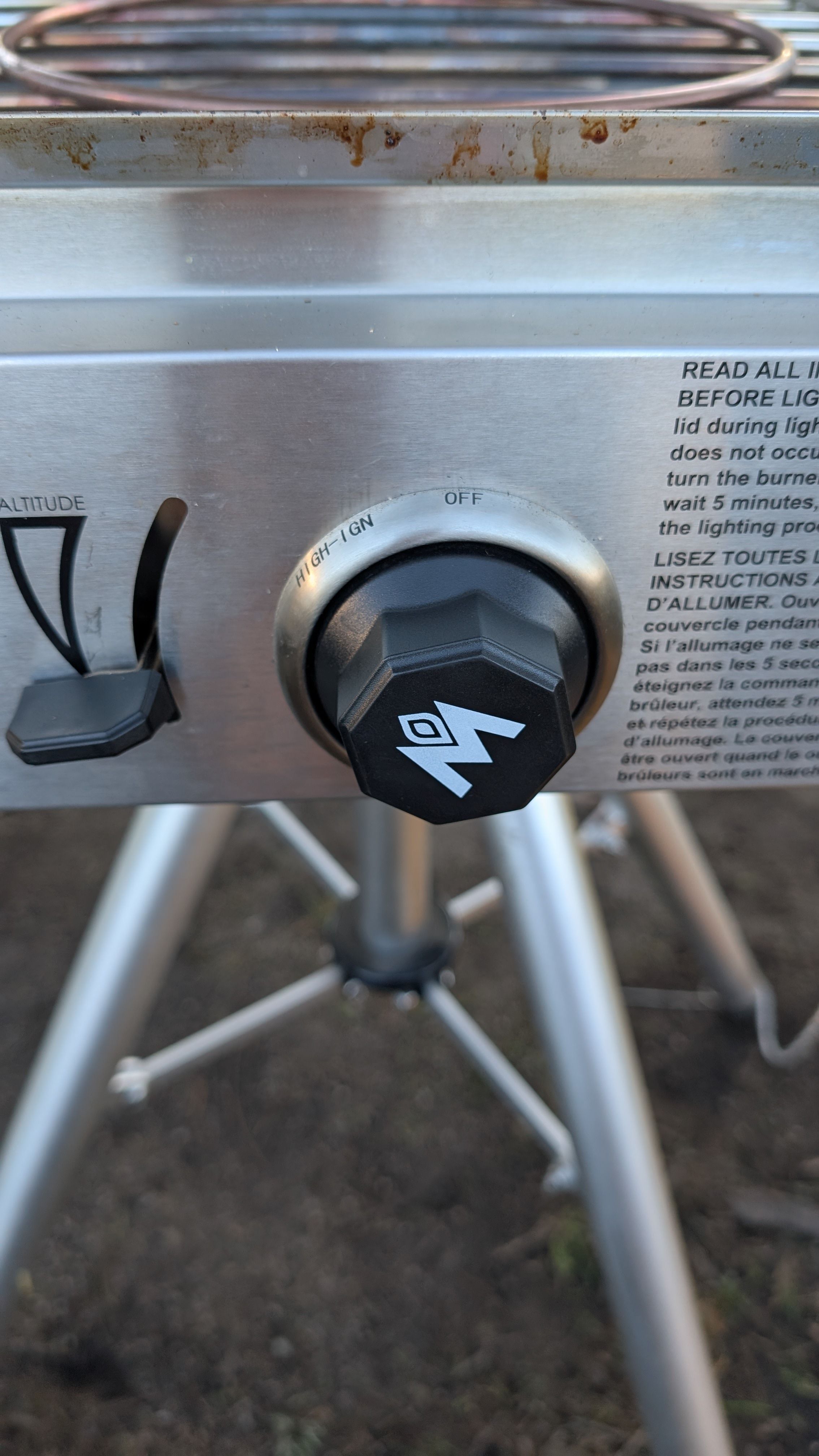 Photo of burner control knob showing OFF and HIGH-IGN positions with safety instructions