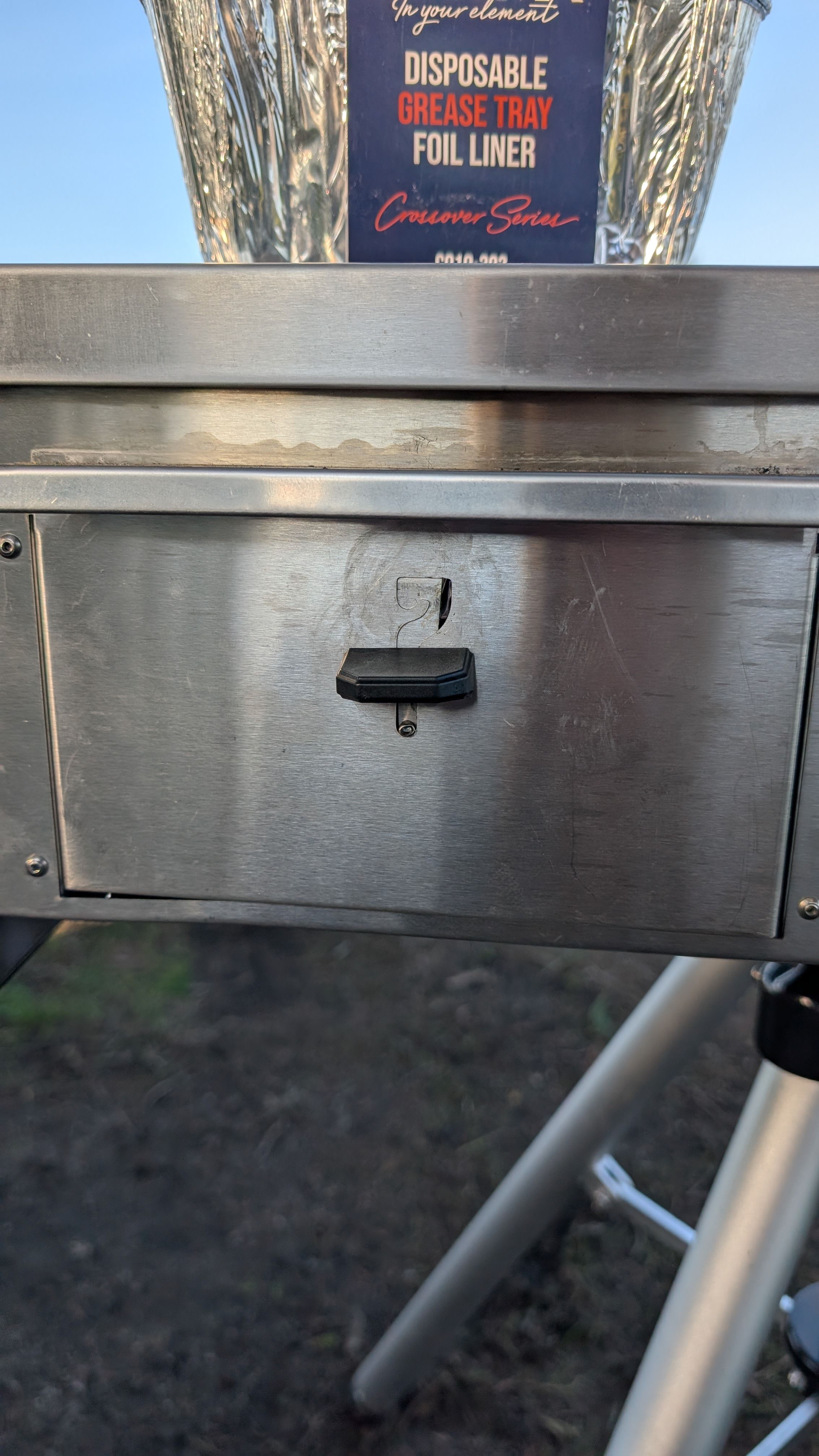 Photo of grease trap latch in the down position with foil liner package visible