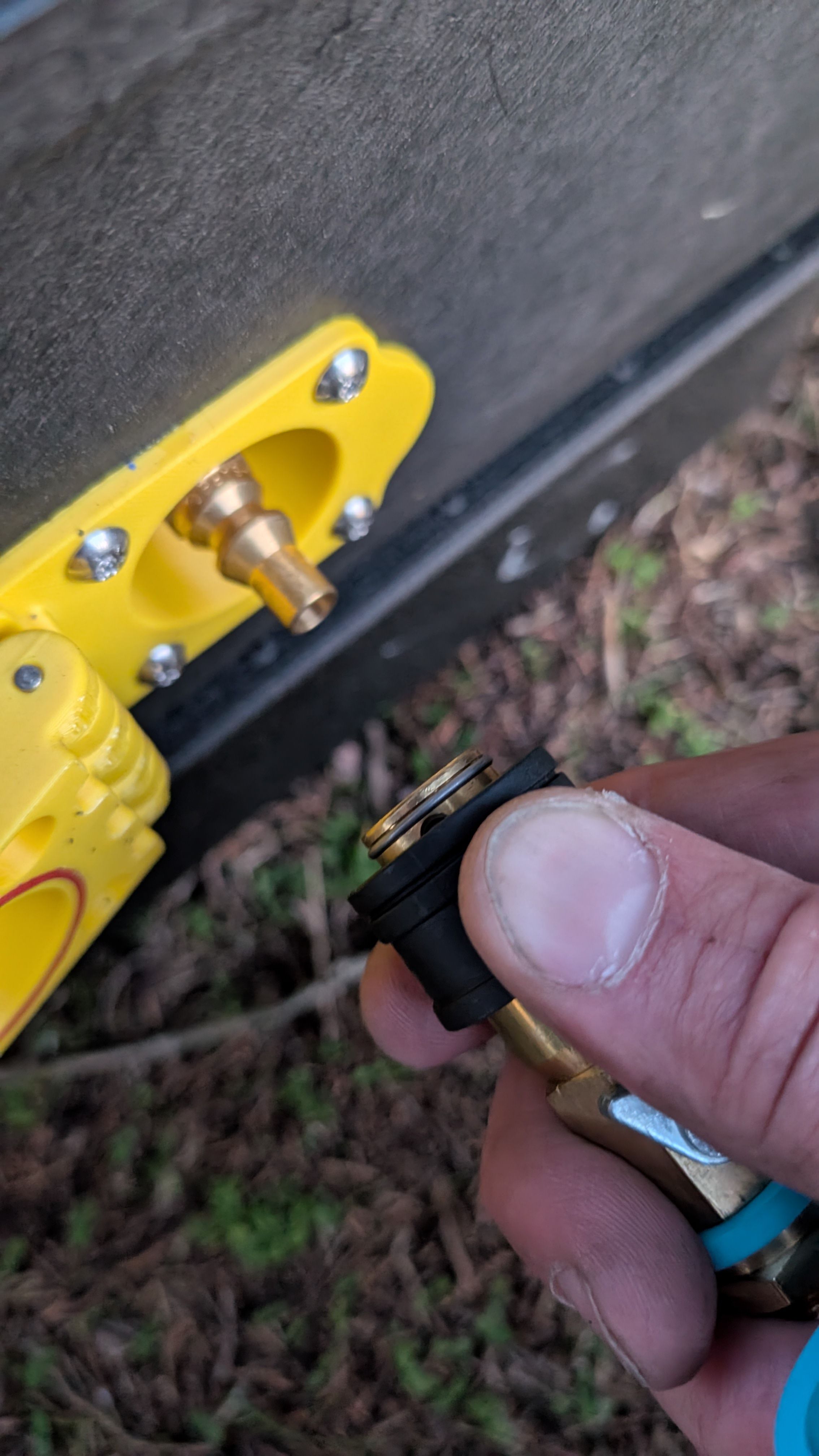 Close-up of hand pulling back quick-connect lock sleeve on propane fitting