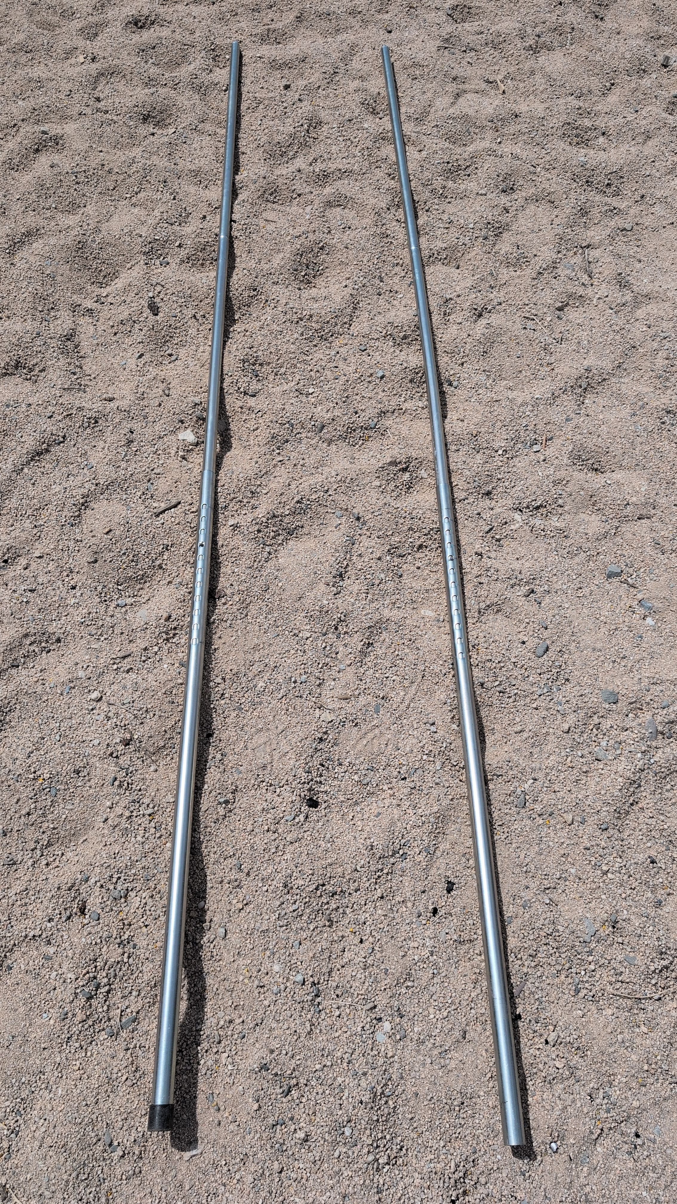Photo of two long upright poles connected with button near top of holes