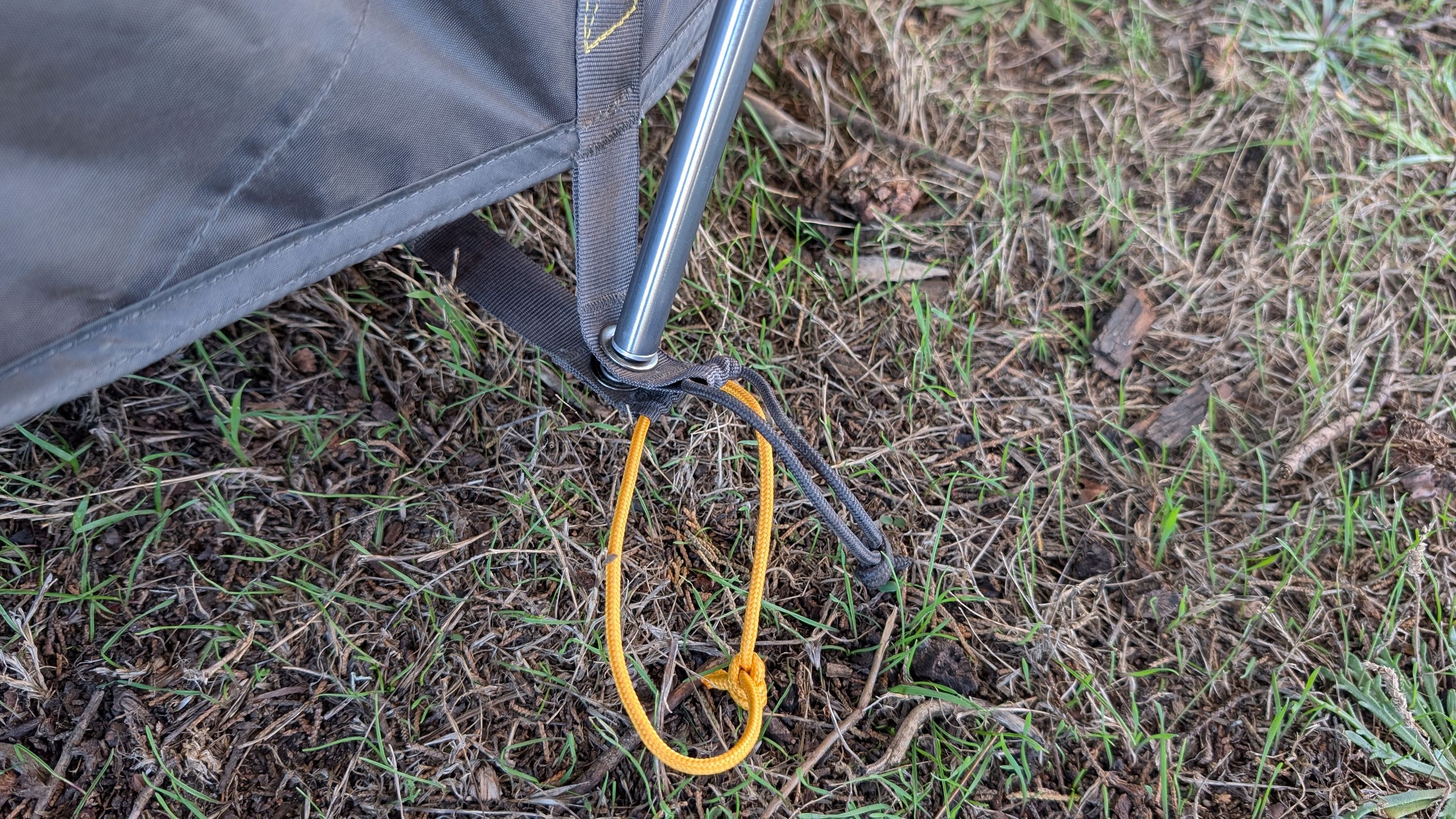 Close-up of gray pole end in tent and orange ground sheet grommet