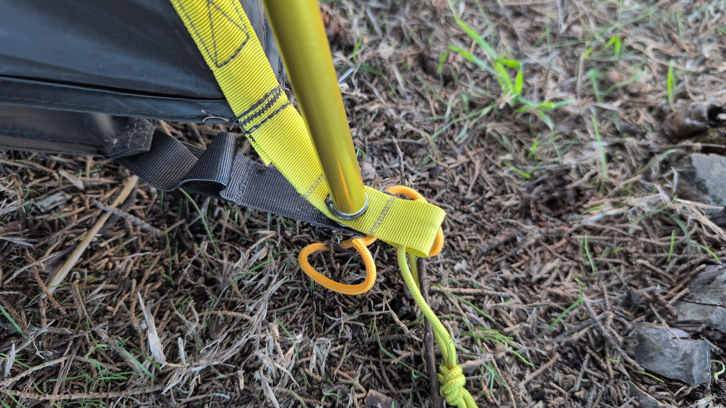 Close-up of pole end being inserted through tent grommet and ground sheet grommet
