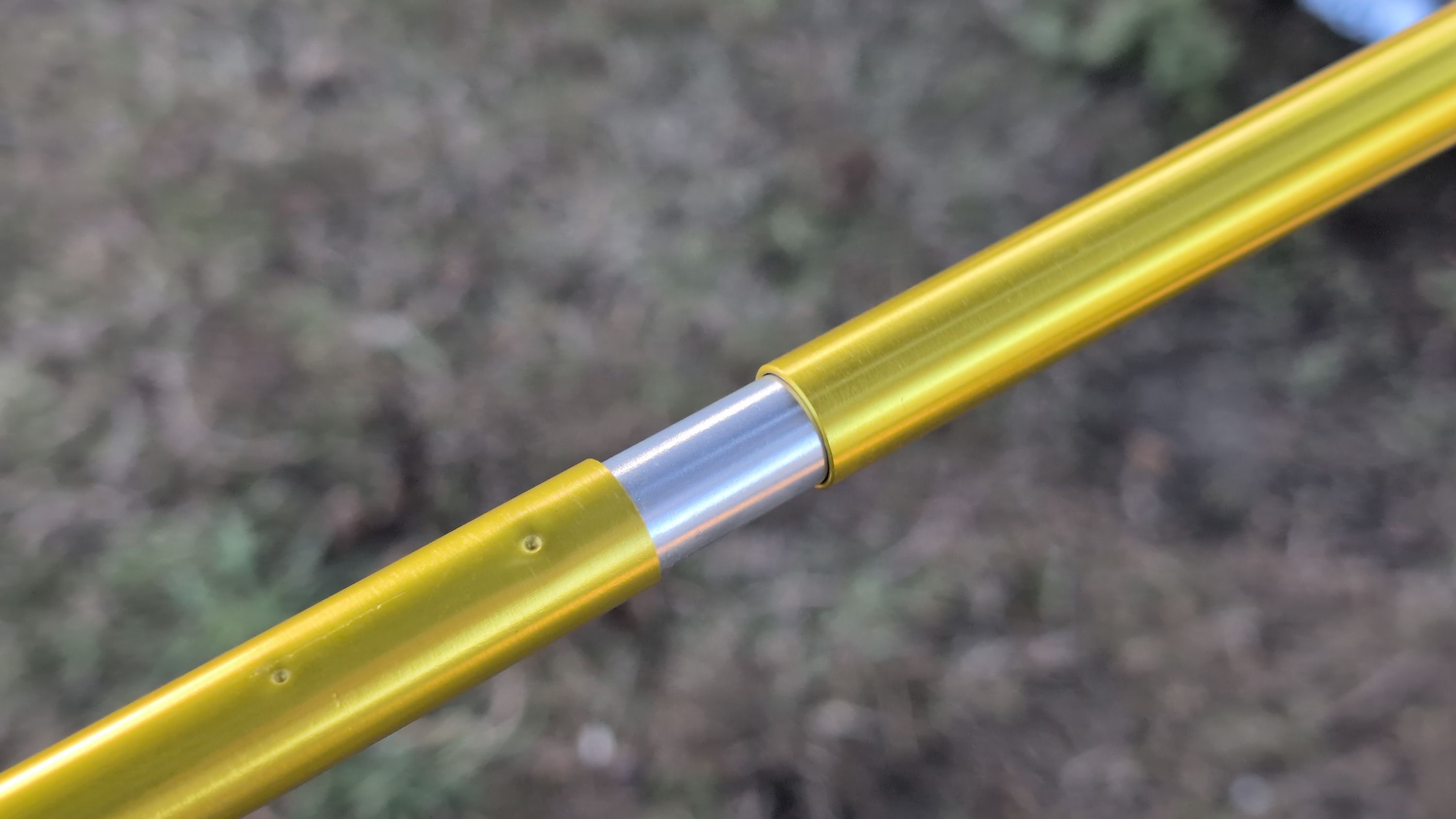 Close-up photo of long yellow pole sections being connected