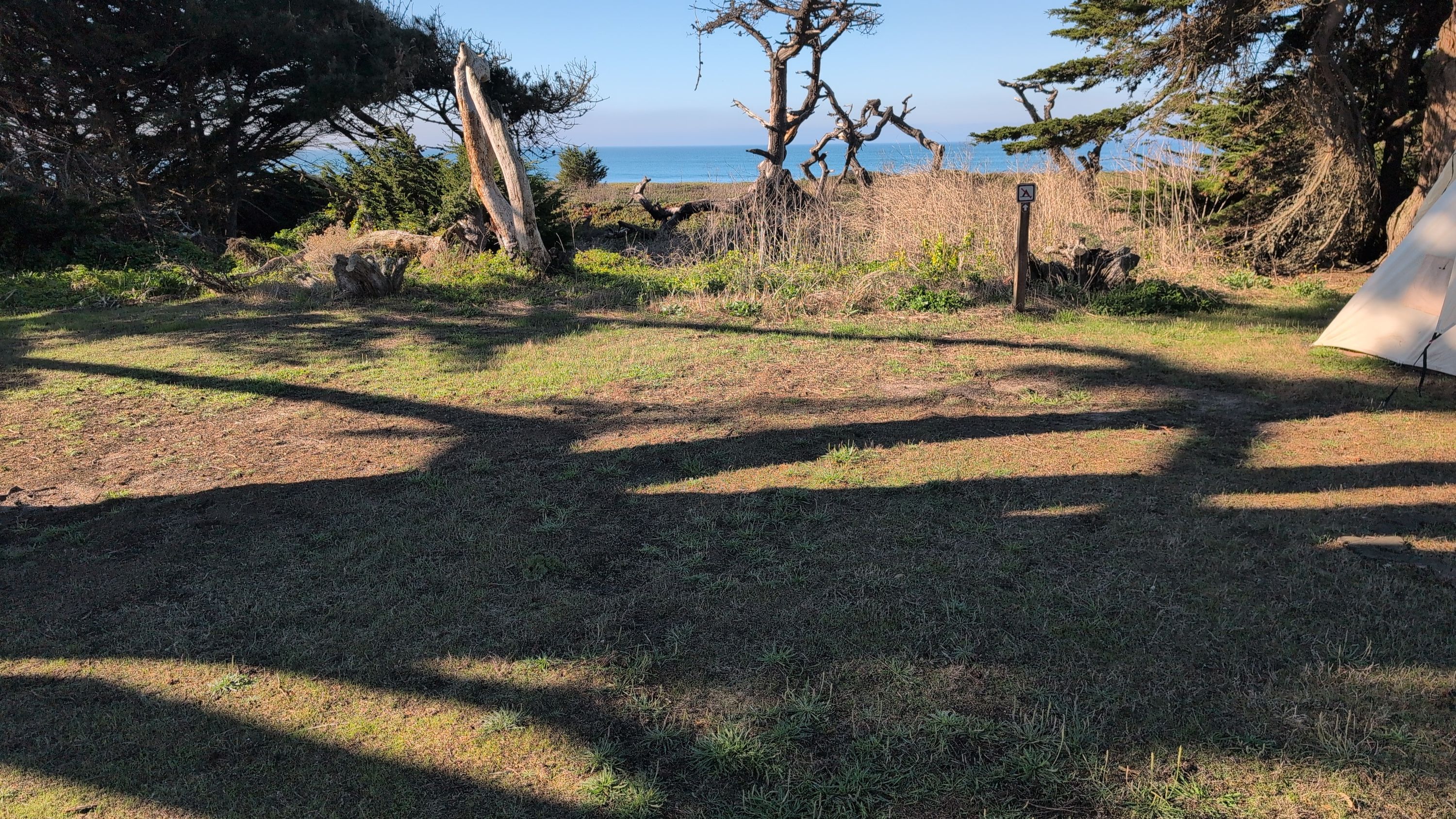 Photo of ideal campsite with flat ground cleared and tent bag for scale