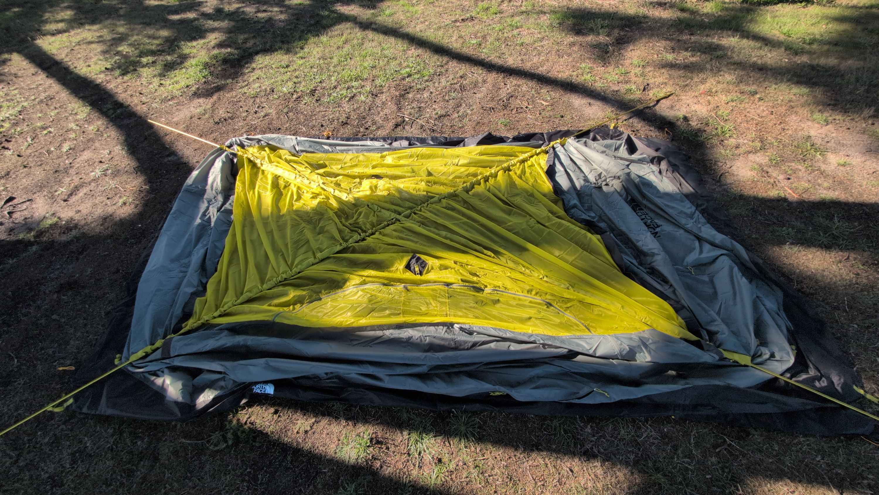 Photo showing both long yellow poles crossed in an X while tent is flat